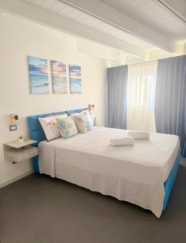 a bedroom with a large white bed with blue accents at B&Suite Le Meraviglie in Terrasini