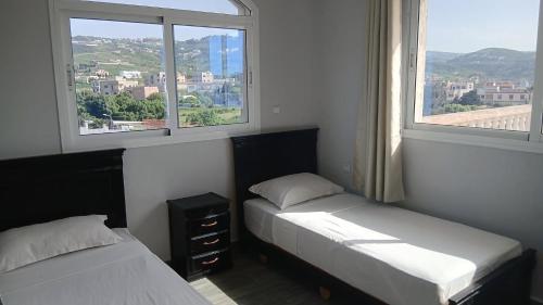 two beds in a room with two windows at Andalus Sunset in Tangier