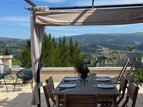 a wooden table with chairs and an umbrella on a patio at Quinta do Olival Amarante in Gatão