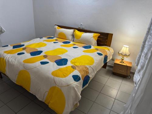 a bedroom with a bed with a yellow and blue comforter at Noble Villa in Abidjan