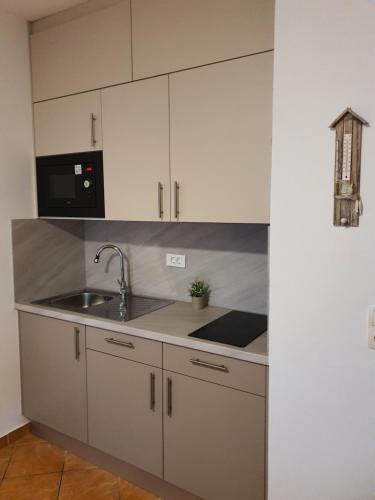 a kitchen with white cabinets and a sink and a microwave at Villa-Panorama in Drage