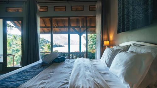 a bed in a bedroom with a large window at Legon Waru Cottage in Karimunjawa