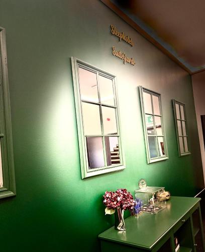 a green wall with two windows and a vase of flowers at Sleephotels Suite Garde in Hamburg