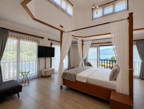 a bedroom with a canopy bed with a view of the ocean at İskelem Otel in Akyaka