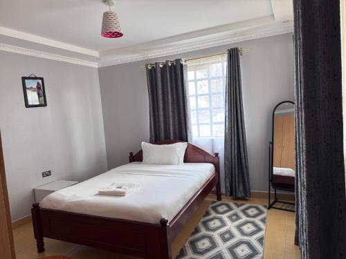 a small bedroom with a bed and a window at Guyana Guest House in Naivasha