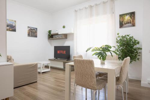 a white dining room with a table and a tv at Aura Station Ciampino 'Roma, StazioneFS, Aeroporto' in Ciampino