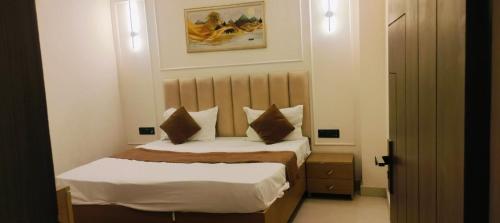 a small bedroom with a bed with white sheets and pillows at hotel elite inn in Greater Noida