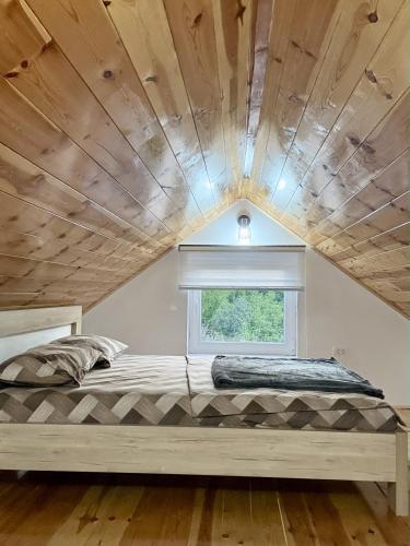 a bed in a room with a wooden ceiling at Lake Apartment Krupac in Nikšić