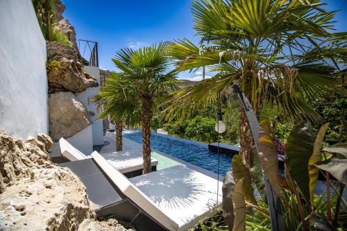 a pool with two lounge chairs and palm trees at XUQ Hotels Lomas de Ruvira in Jorquera