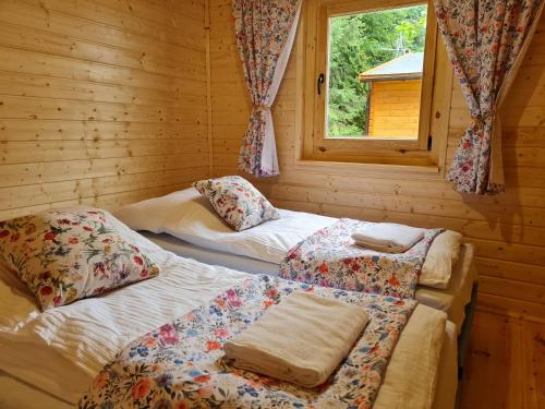 two beds in a log cabin with a window at Pensjonacik Ogrody in Pierzchno