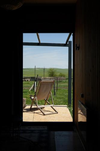 a wooden chair sitting on a porch with a view of a field at Oasis Club Cottages in Udabno