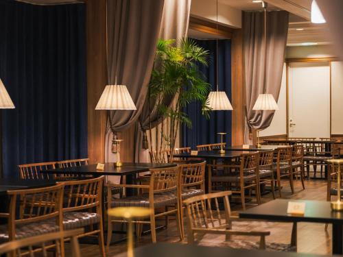 a dining room with tables and chairs and plants at Oarai Park Hotel in Oarai