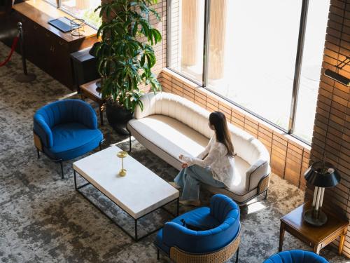 a woman sitting on a couch in front of a window at Oarai Park Hotel in Oarai