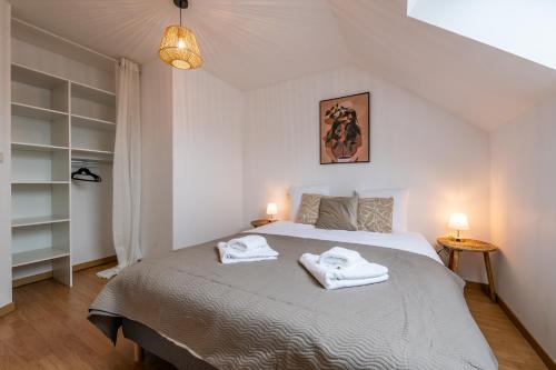a bedroom with a large bed with towels on it at Le Triplex - cosy avec petit jardin in Longueville