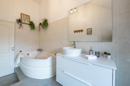 a white bathroom with a tub and a sink and a bath tub at Le Triplex - cosy avec petit jardin in Longueville