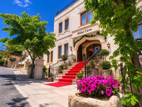 a building with red stairs in front of it with pink flowers at Milat Cave in Göreme
