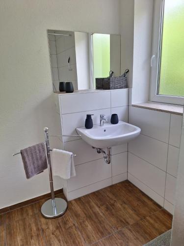 a white bathroom with a sink and a mirror at Ferienwohnung Bever in Bad Karlshafen