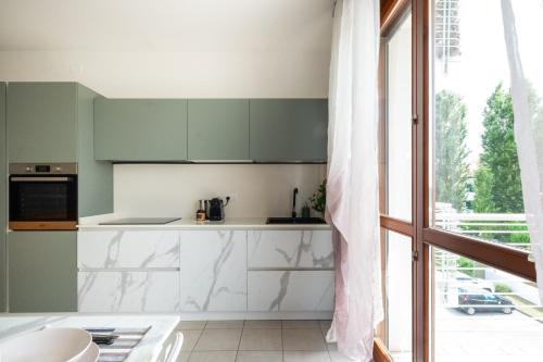 a kitchen with green and white cabinets and a window at Ca'vio Beach Pool in Cavallino-Treporti