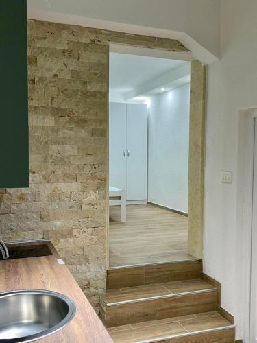 a bathroom with a sink and a stone wall at Relax Apartmani in Sutomore