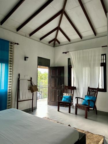 a bedroom with a bed and two chairs and a door at One Bhakthi in Ahangama