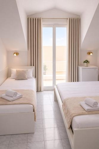 two beds in a white room with a window at All inclusive Villa Four Pearls in Trogir