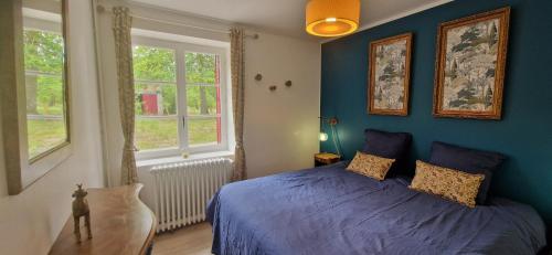 a blue bedroom with a bed and two windows at Le Fourneau Rond in Soings-en-Sologne