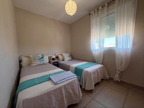 two beds in a small room with a window at Delfines III Solo Familias Serviplaya in Playa de Xeraco