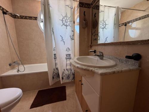 a bathroom with a sink and a toilet and a shower curtain at Delfines III Solo Familias Serviplaya in Playa de Xeraco