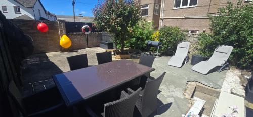 a patio with a table and chairs in a backyard at Spacious Coastal Apartment with Garden Pet Friendly in Rhos-on-Sea
