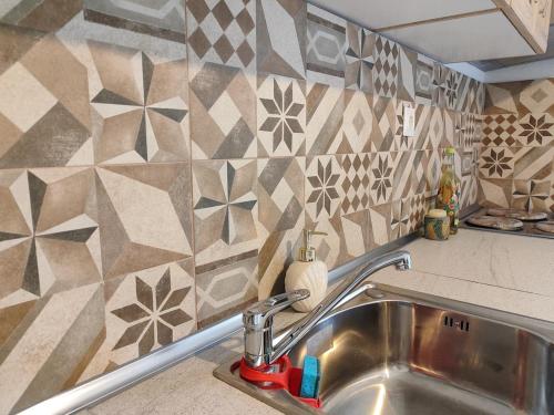 a kitchen with a sink and a tiled wall at Citrus Home in Chorefto