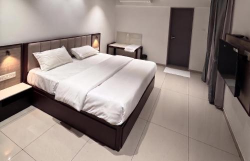 a bedroom with a large bed with white sheets at Bala Saraswathi Residency in Tuticorin