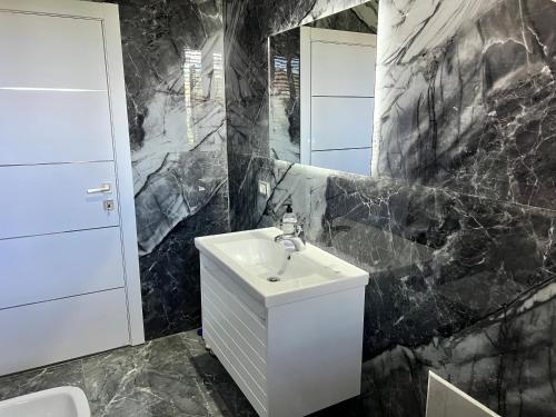 a black marble bathroom with a sink and a mirror at Host Apartments in Shkodër