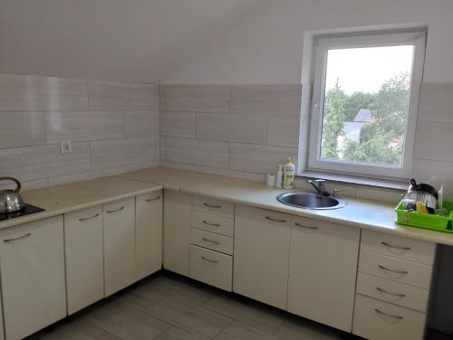 a kitchen with white cabinets and a sink and a window at Hostel Pod Lasem in Altanka