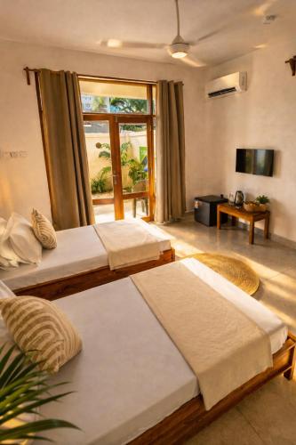 a hotel room with two beds and a television at Smile Boutique Beach hotel in Nungwi