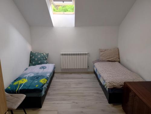a small room with two beds and a window at Hostel Pod Lasem in Altanka