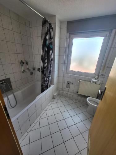 a bathroom with a tub and a toilet and a window at Aparthotel Boardinghouse BRACK mit Parkplatz Küche WIFI in Bielefeld