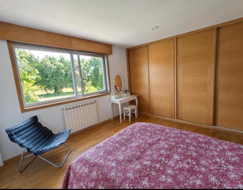 a bedroom with a bed and a chair and a window at CASA Arce in Boqueijón