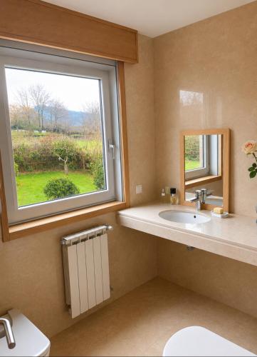 a bathroom with a sink and a window at CASA Arce in Boqueijón