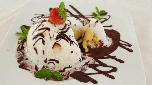 a dessert with ice cream and a strawberry on a white plate at Hotel Regina in Alassio