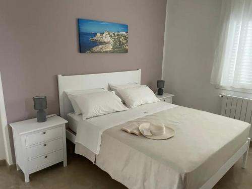 a bedroom with a white bed with a hat on it at Le 2 vele in Cerfignano