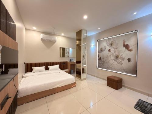 a bedroom with a bed and a painting on the wall at Hotel Shree Maya Comfort Inn in Ujjain