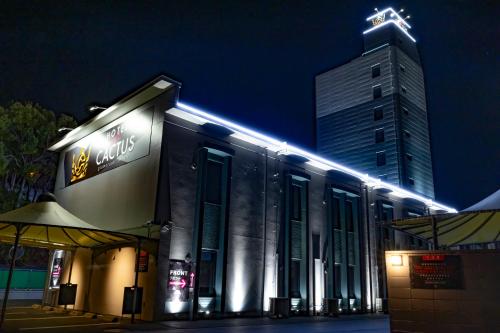 ein Gebäude mit Lichtern darauf mit einem hohen Gebäude in der Unterkunft HOTEL the CACTUS in Kasugai