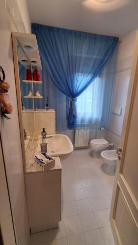 a bathroom with a sink and a toilet and a blue curtain at Casa Bibi in Subbiano