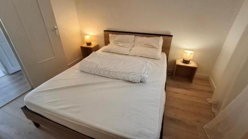 a bed with white sheets and pillows in a room at A Casa Radica, appartement rez-de-villa au calme, jardin et maquis in Eccica-Suarella