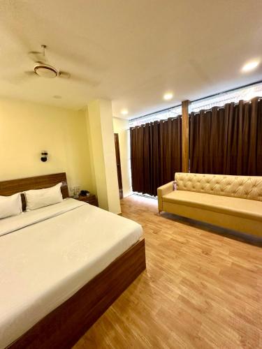 a bedroom with a large bed and a couch at Hotel Tu Casa in Kolkata