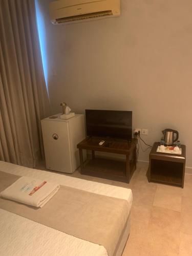 a room with a bed and a tv and a table at Hotel room in Salalah