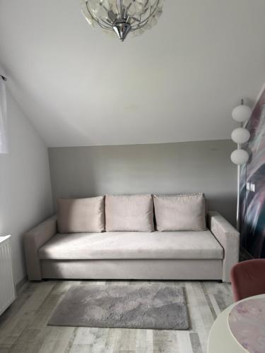 a white couch in a living room with a chandelier at Apartament nad jeziorem in Lubkowo