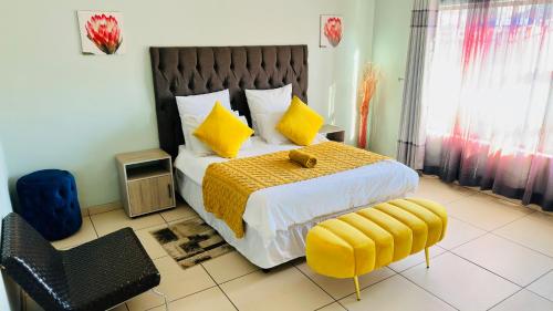 a bedroom with a bed with yellow pillows and a chair at Nyasa Villa in Southgate
