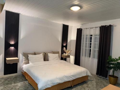 ein Schlafzimmer mit einem großen weißen Bett und schwarzen Vorhängen in der Unterkunft Zenaida in Paramaribo