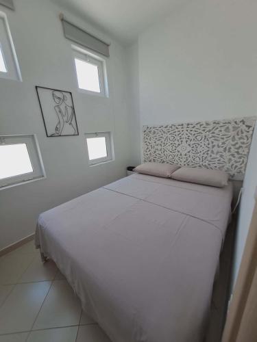 a white bedroom with a bed with four windows at Mimosa Apartment in Vlorë